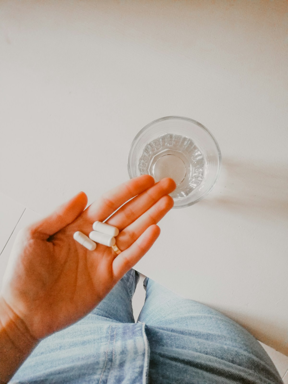 Natural sleep supplements including CBD oil and melatonin capsules on white surface