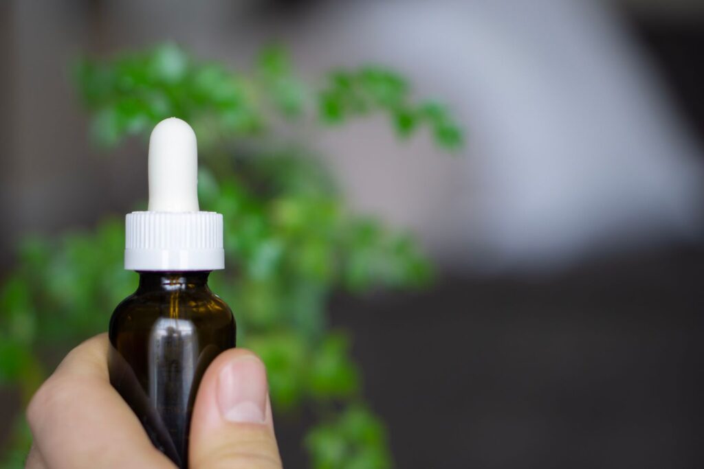 Dropper bottle of CBD oil against a botanical background