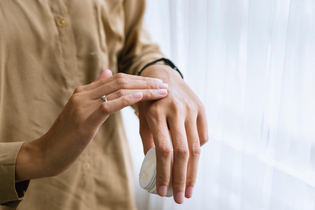 Person applying moisturizing lotion to skin as part of a skincare routine
