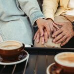 Mature couple holding hands over coffee