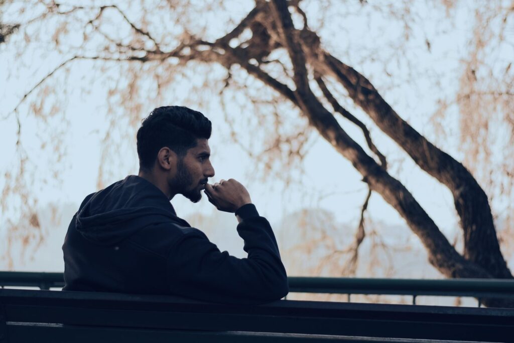 Person sitting alone outdoors, calm and thoughtful expression