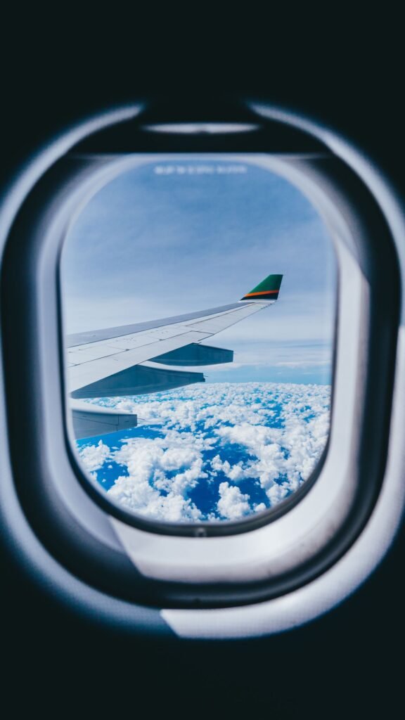 View of an airplane wing above the clouds through a cabin window, for travelers flying with CBD