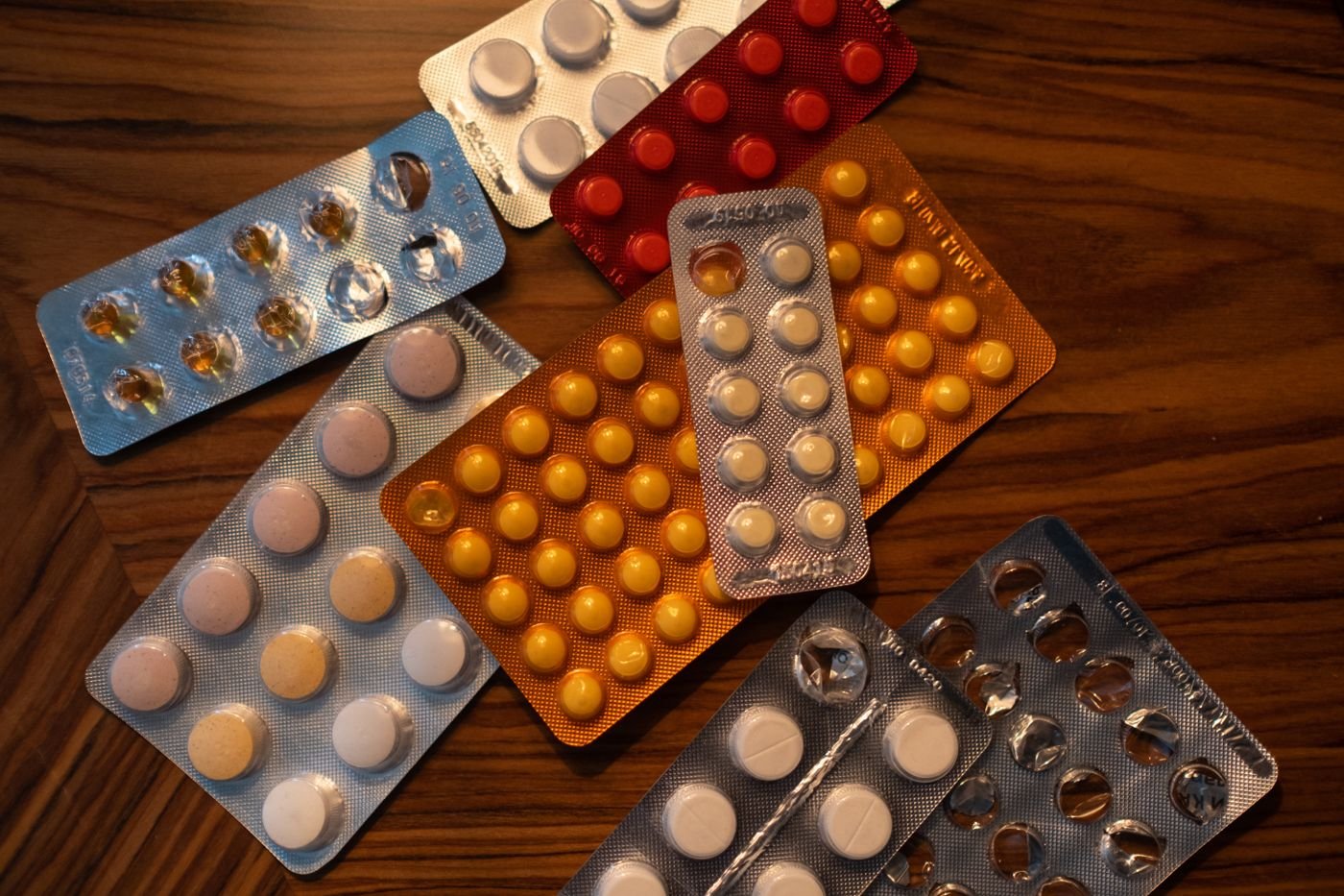 Blister packs of assorted tablets on a wooden table, a reminder to check CBD interactions with other medication