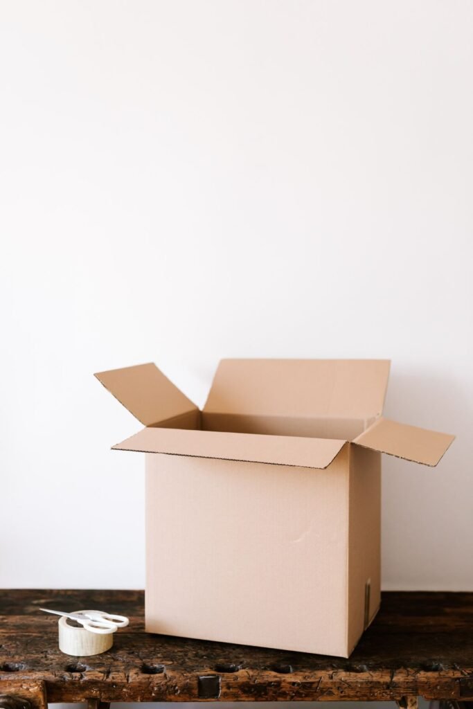 An open empty cardboard shipping box on a wooden table, ordering CBD oil online for delivery in Canada