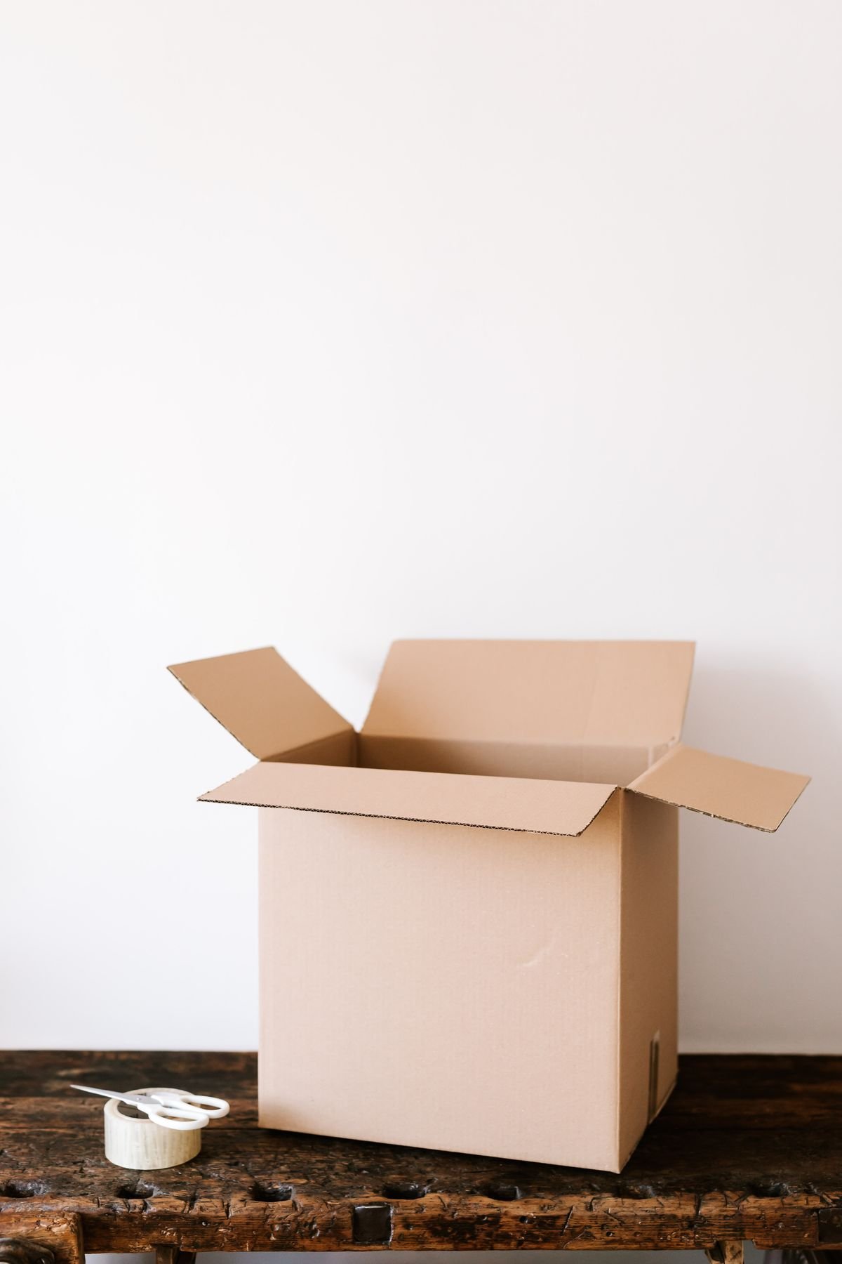 An open empty cardboard shipping box on a wooden table, ordering CBD oil online for delivery in Canada