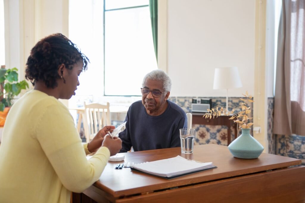 Caregiver going over medication with an older man at home, discussing the Medicare CBD pilot program