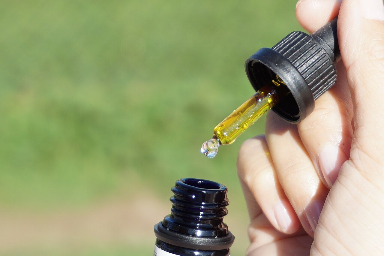 Close-up of a dropper releasing CBD oil into a bottle, illustrating daily dosage for CBD supplements