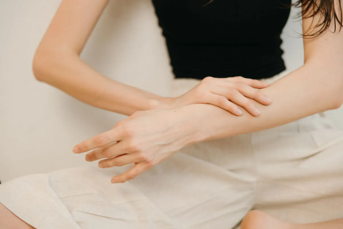 Person applying a topical product to the forearm, the way a CBD roll-on is massaged into the skin