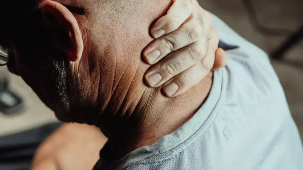 Man holding his sore neck and shoulder, the kind of localised ache a CBD freeze roller is applied to