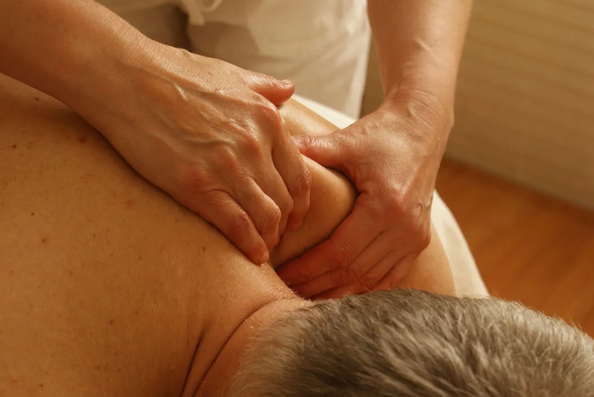 Hands working on a sore shoulder muscle for targeted pain relief