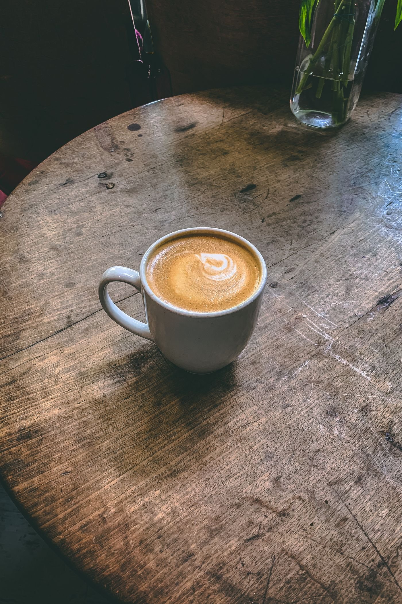 Cup of coffee on a rustic round wooden table in a cafe