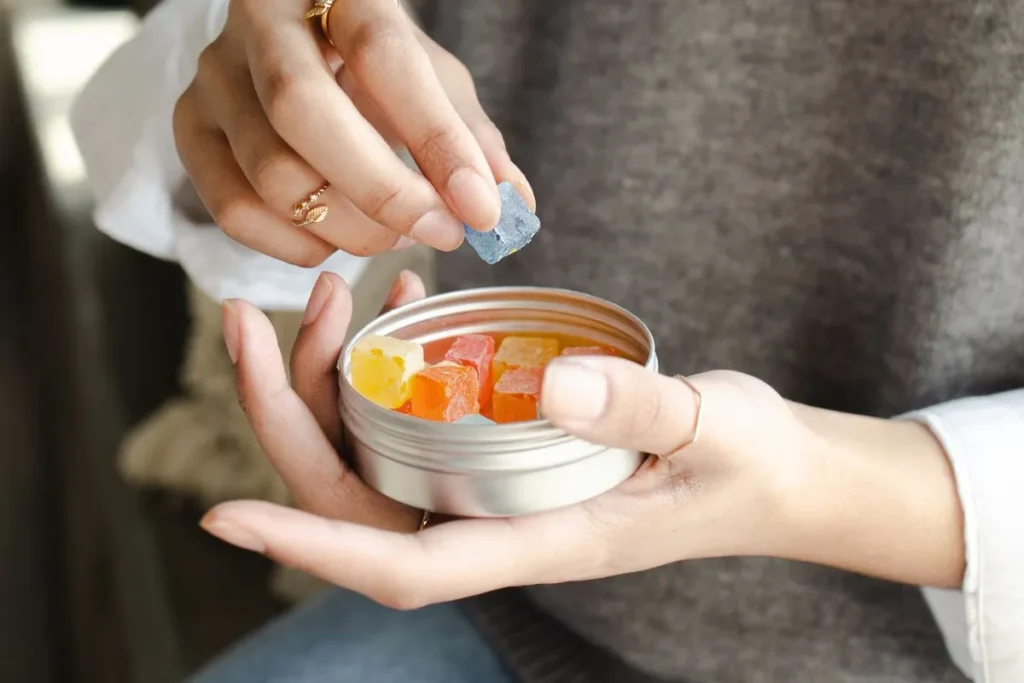Hand taking a hemp gummy from an open tin, illustrating a hemp gummies review for buyers in Israel