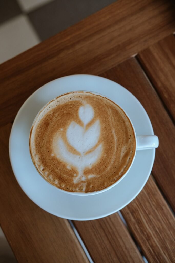 Cup of latte with foam art on a wooden table, for readers mixing CBD and caffeine