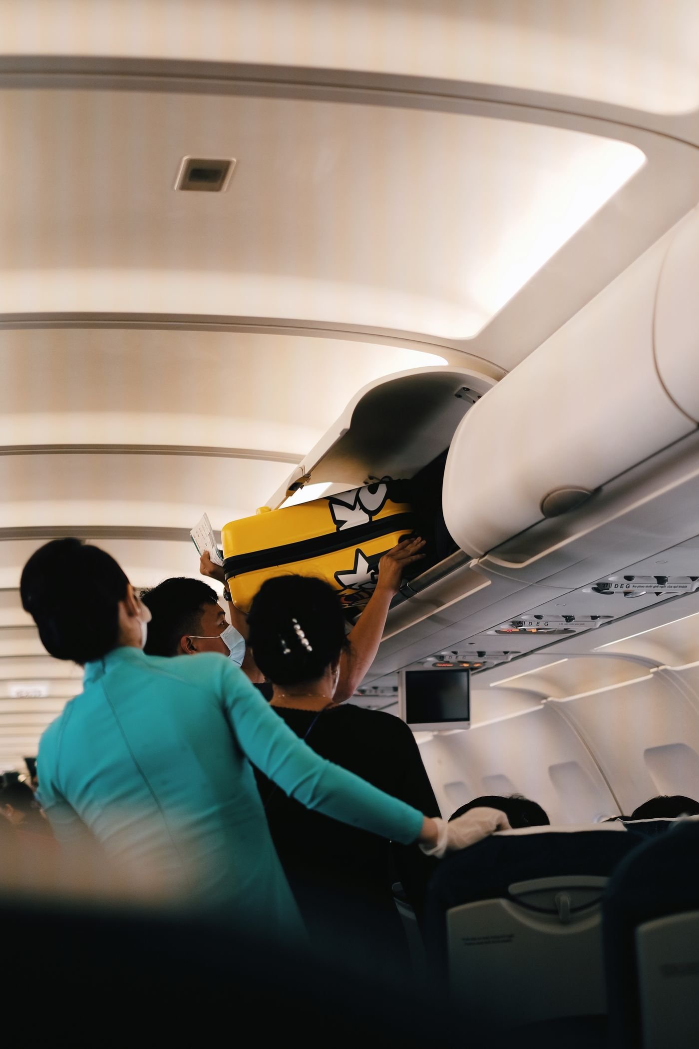Passengers placing a suitcase in the overhead bin of an airplane cabin