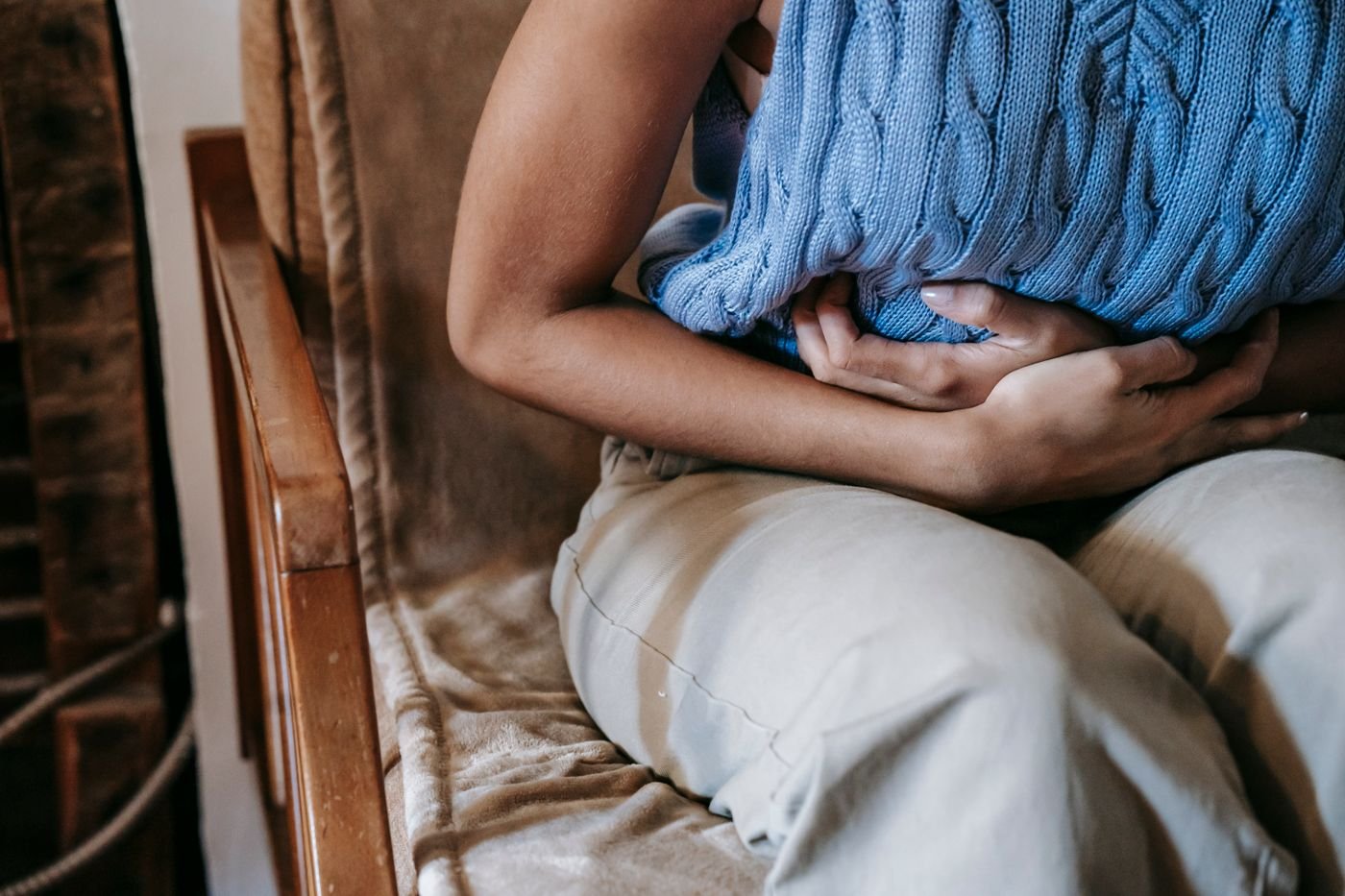Person sitting in a chair holding their stomach, a common side effect when starting GLP-1 medications