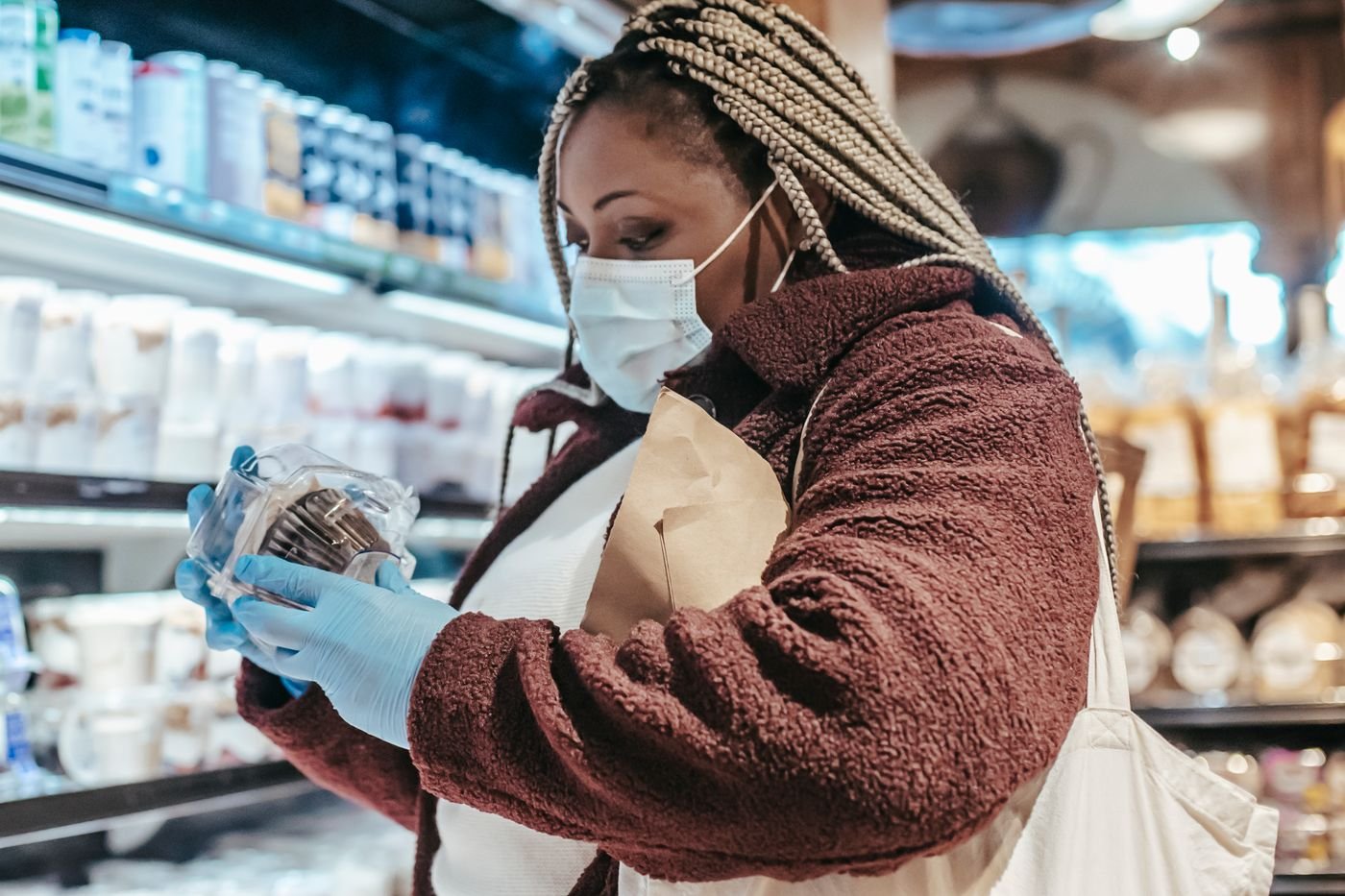 Shopper reading the label on a product in a store, checking ingredients before buying