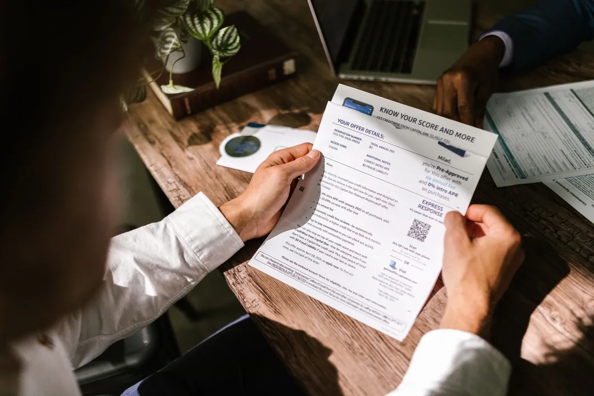 Hands holding a printed report at a desk, checking the figures line by line