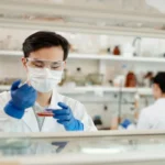 Lab researcher in gloves and safety glasses testing a sample, like the labs behind CBD certificates of analysis